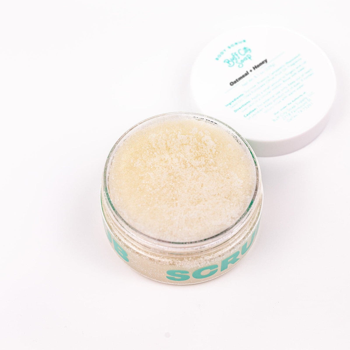 open container of Oatmeal + Honey Body Scrub with lid placed next to it