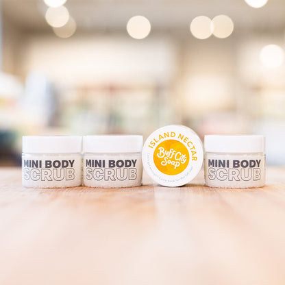 Four Mini Island Nectar Body Scrubs in containers lined up on counter