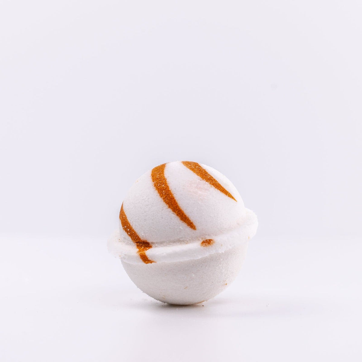 a white Narcissist Bath Bomb, with caramel design, placed upright
