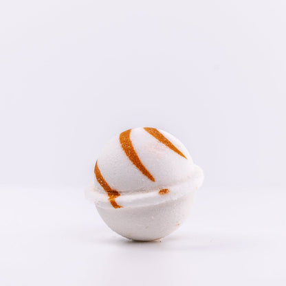 a white Narcissist Bath Bomb, with caramel design, placed upright